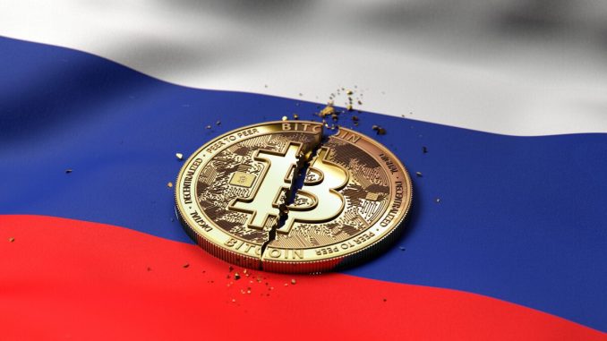 A cracked token representing Bitcoin rests on a Russian flag.