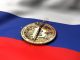 A cracked token representing Bitcoin rests on a Russian flag.